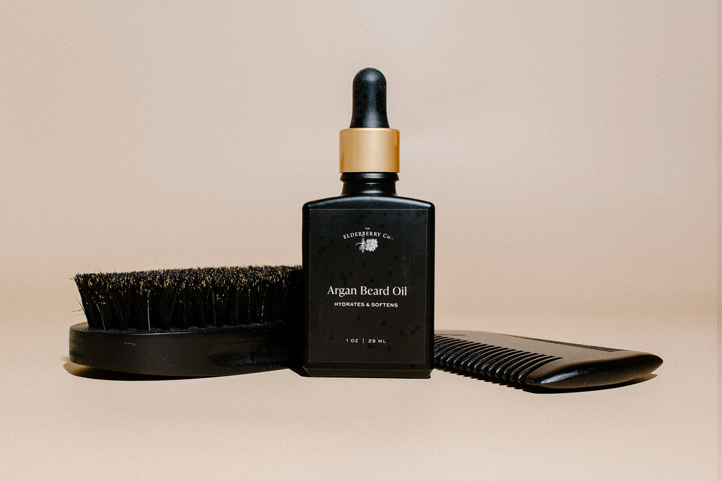 Elderberry Co. Argan Beard Oil with a wooden beard brush and styling comb, showcasing a complete beard grooming set for hydration, softening, and daily beard care.