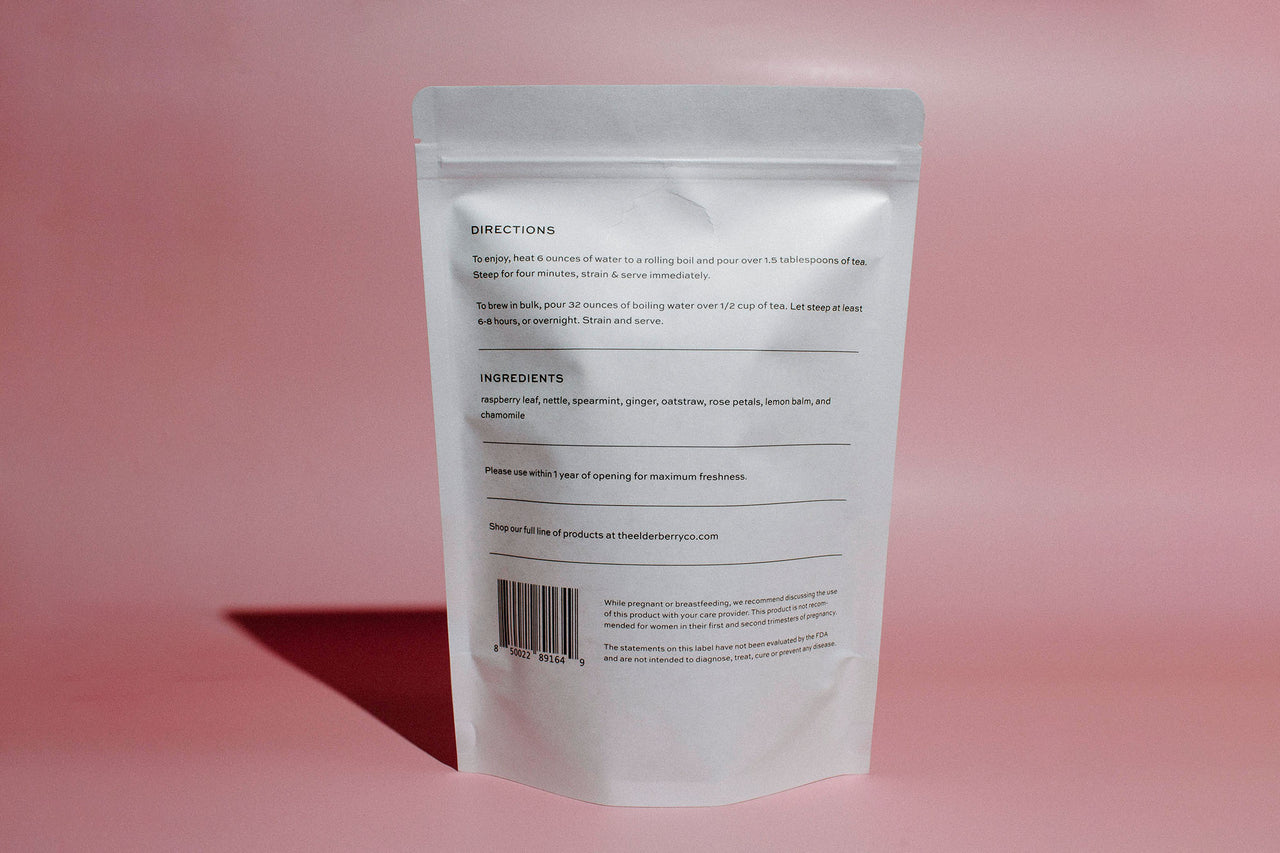 A stand-up pouch of Elderberry Co. Raspberry Tea back on a solid pink background.