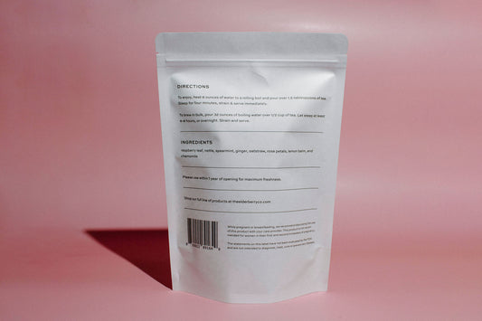 A stand-up pouch of Elderberry Co. Raspberry Tea back on a solid pink background.