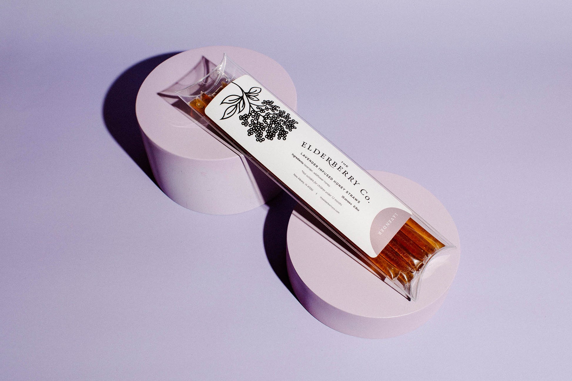 Bar of soap with a label on a purple stand against a light purple background