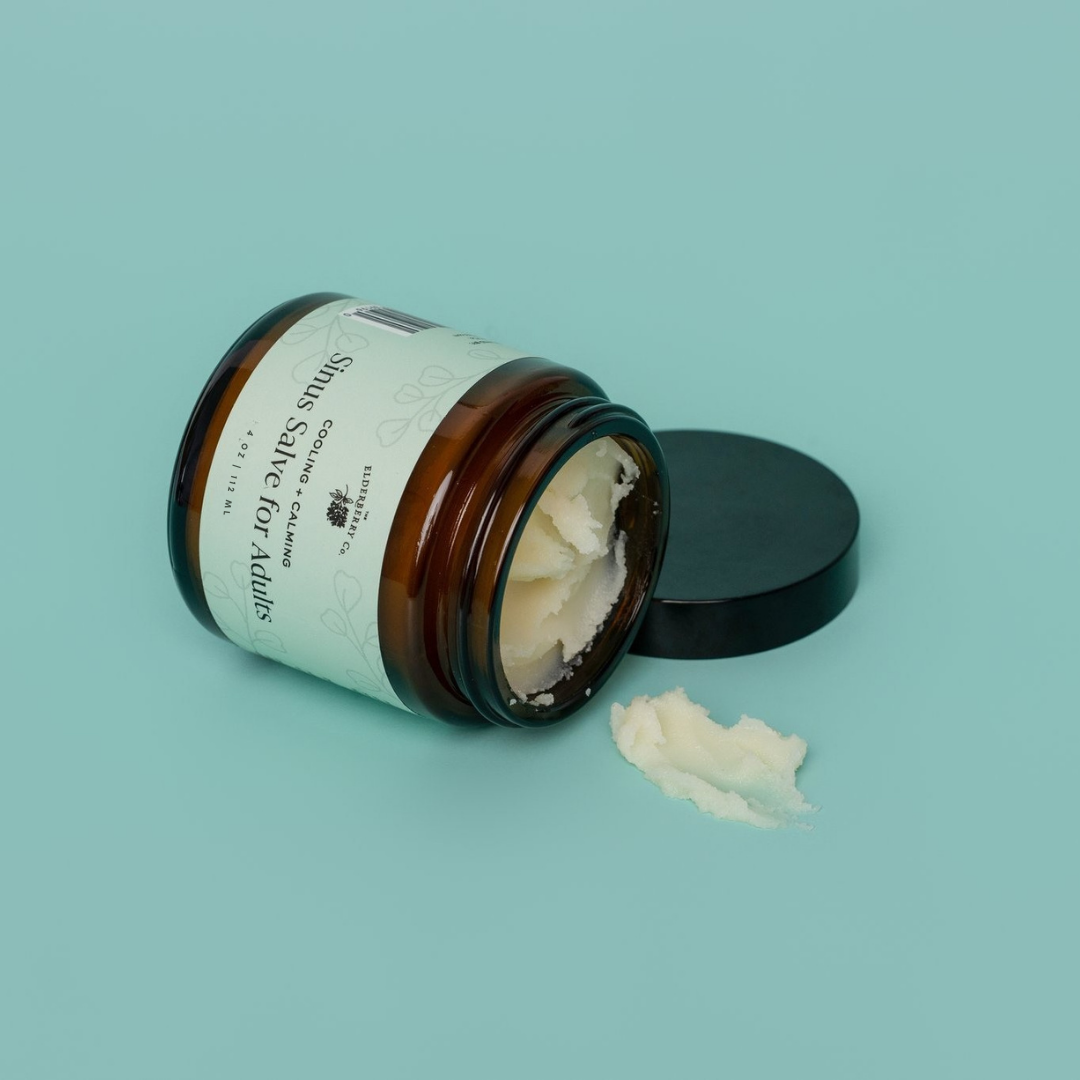 Open jar of cream with a black lid on a light blue background
