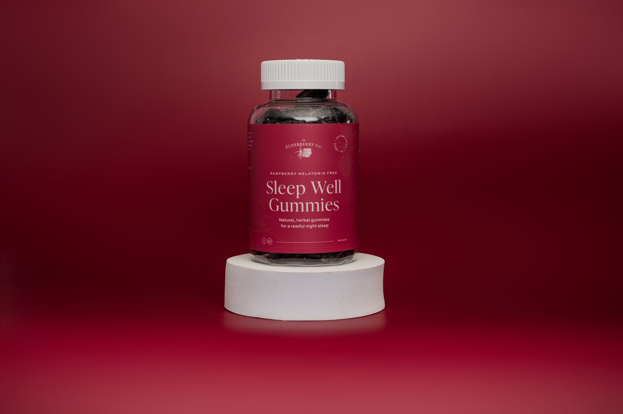 A bottle of Sleep Well Gummies on white stand with red background