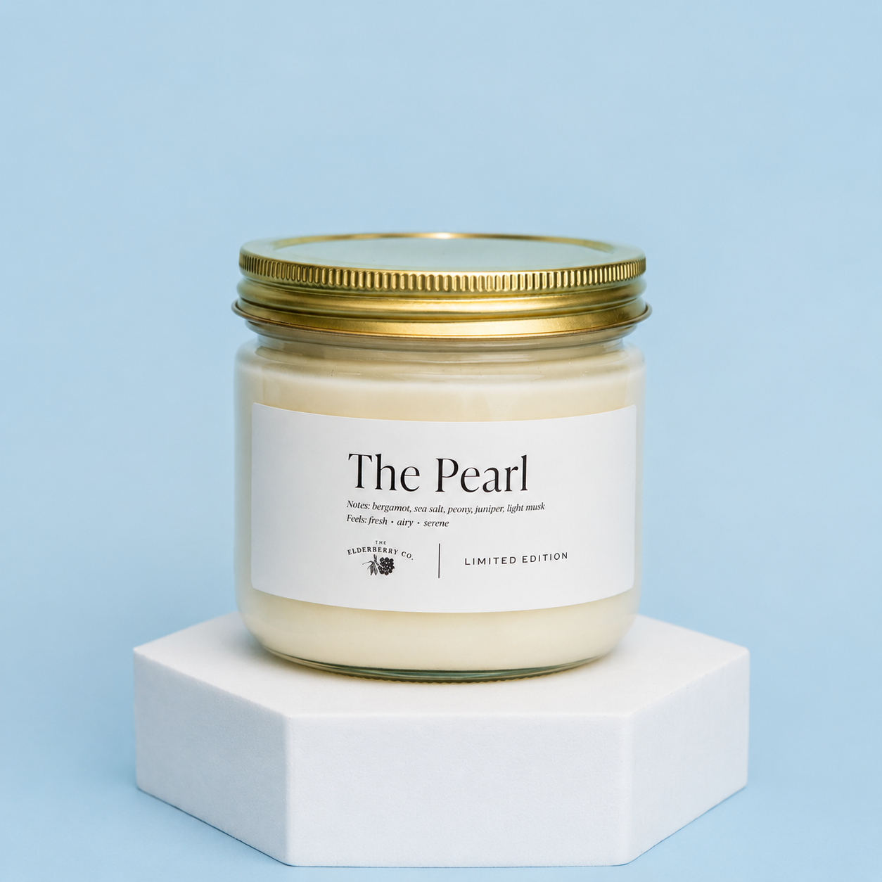 Candle jar labeled 'The Pearl' on a white platform with a light blue background